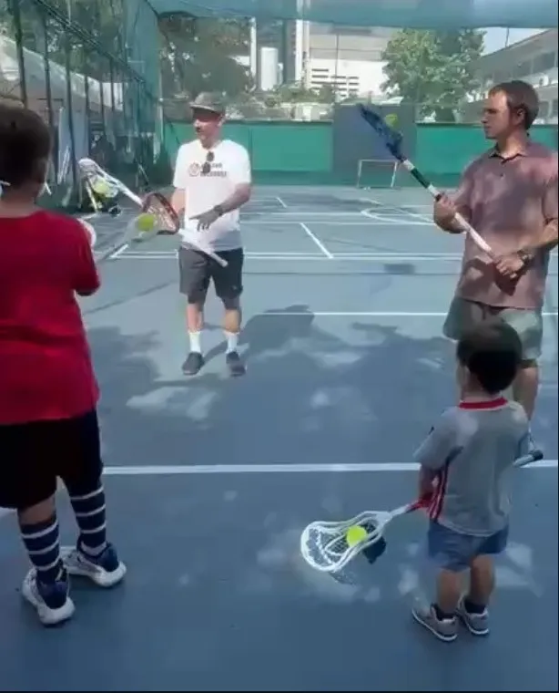 Adults and children passing a ball on an outdoor court